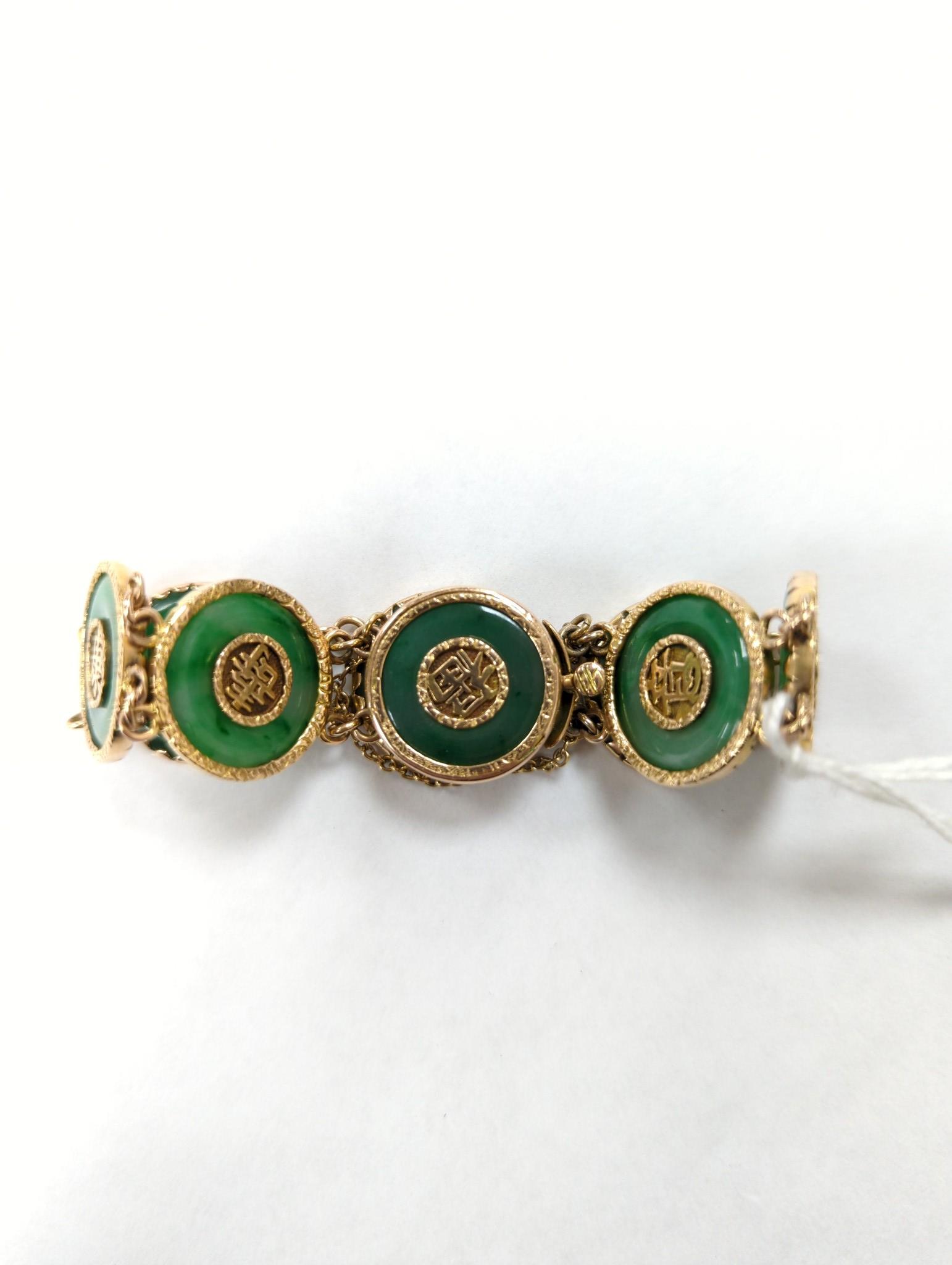 A Chinese yellow metal (stamped 18) and pierced eight stone jade disc set bracelet, with central Chinese characters, 16.5cm approx. gross weight 27.7 grams.